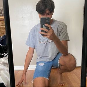 Medium wash distressed and ripped denim jean shorts (jorts).